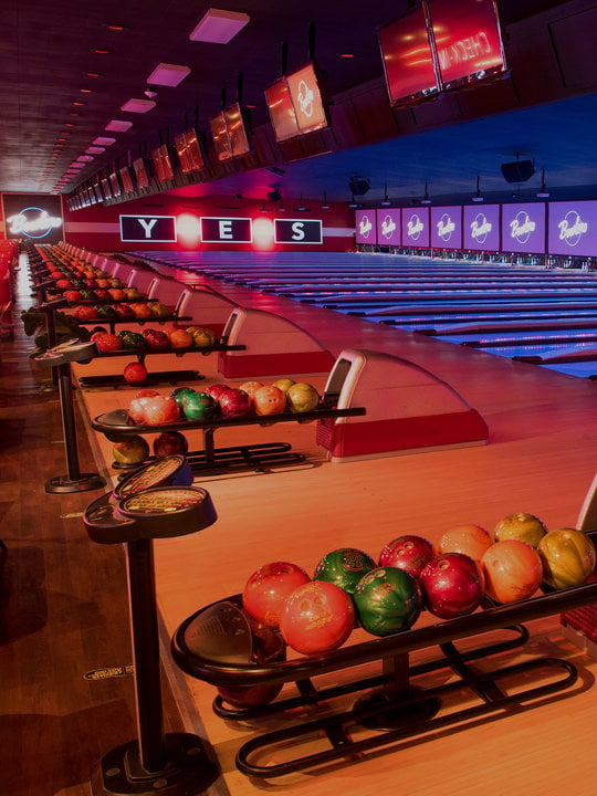Ball returns and bowling lanes with 'YES' written on the wall