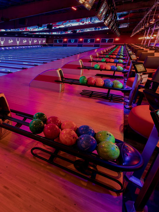 Ball returns and bowling lanes with 'LUST' written on the wall