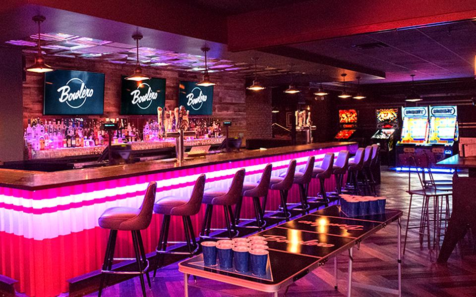 Colorfully lit bowling center bar with Bowlero signs in the background