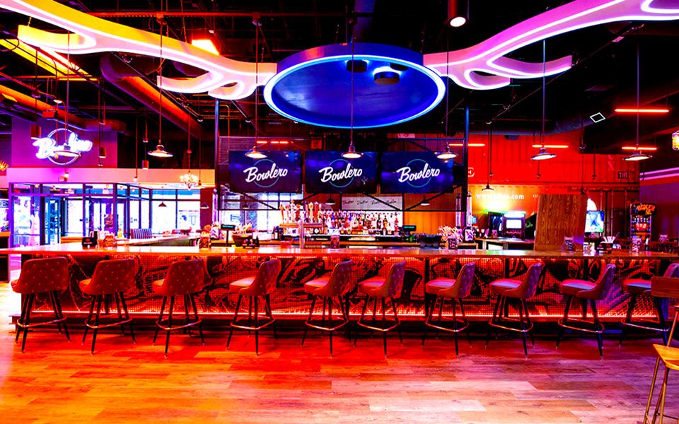 Colorfully lit bowling center bar with Bowlero signs in the background