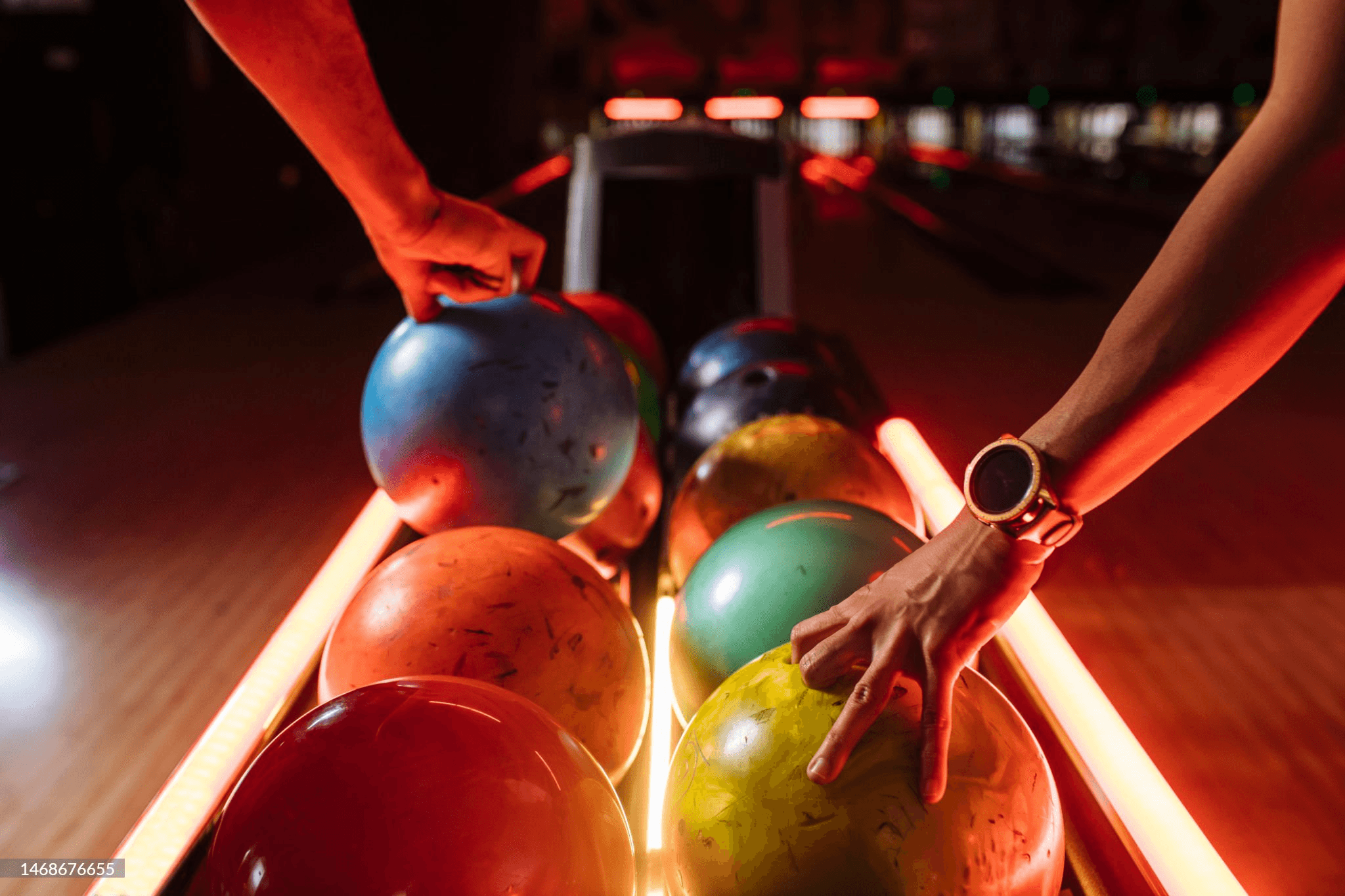 Colorful bowling balls being picked up from ball return