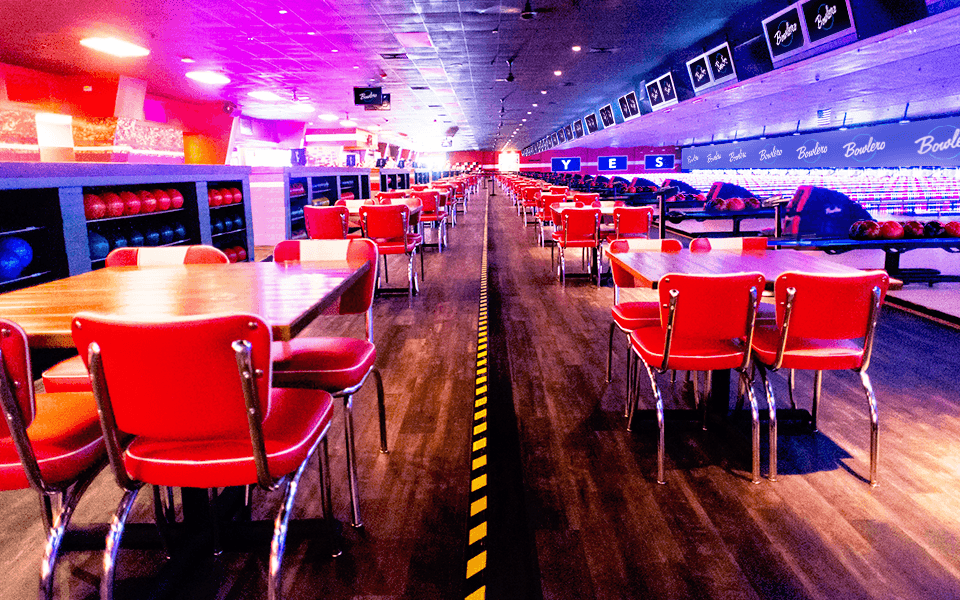 Dining tables in a bowling center with bowling lanes in the background