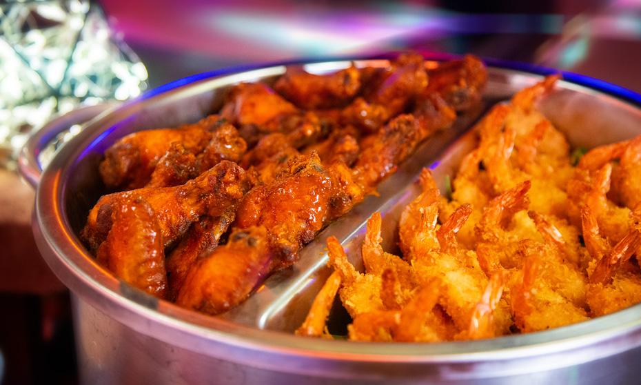 Chicken wings and coconut shrimp displayed in a tin buffet setup. 