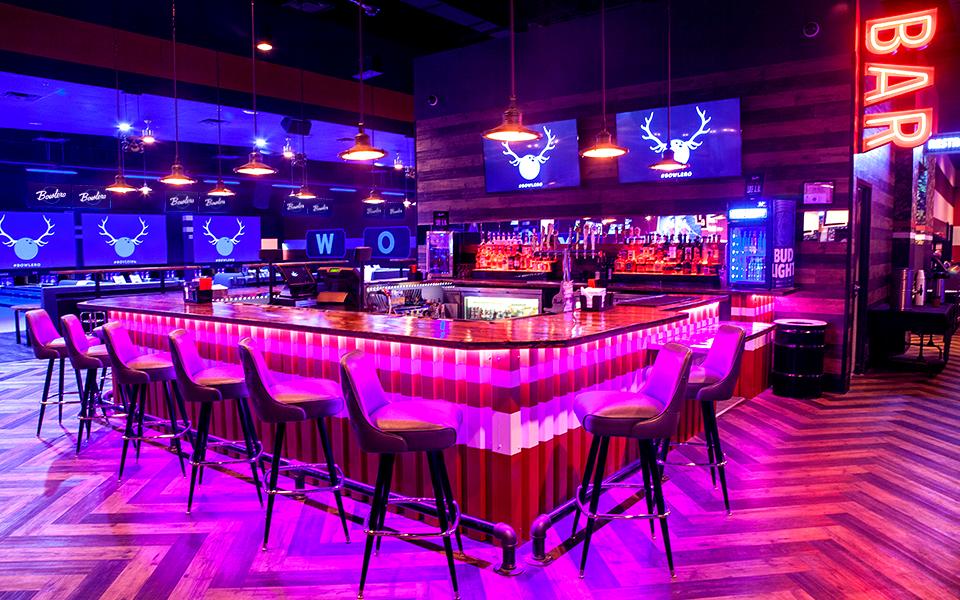 Colorfully lit bar with bowling center in background