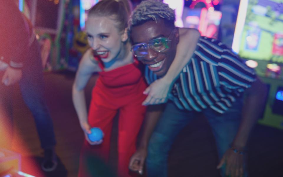 Two pole having fun on a date in the arcade. 