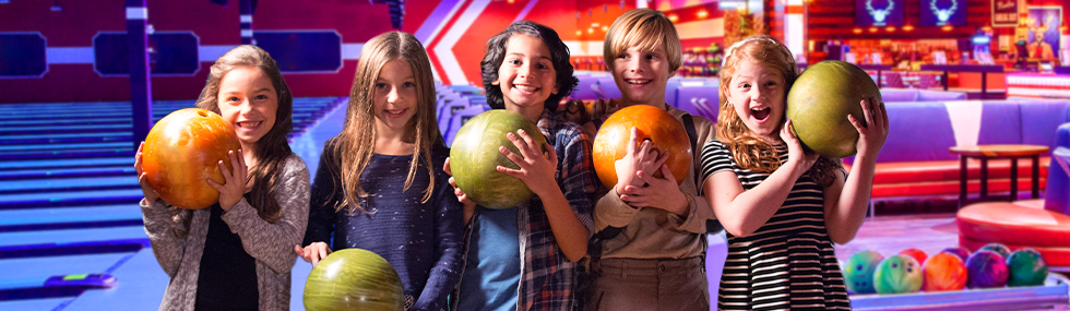 Group of five kids holding bowling balls.