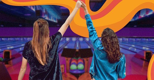 Bowlers holding hands in front of bowling lanes